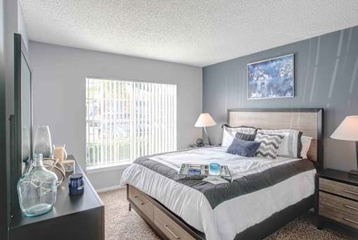 A bedroom with a large bed and a window with blinds.