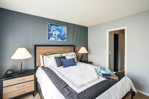 A bedroom with a bed, nightstand, and lamp.