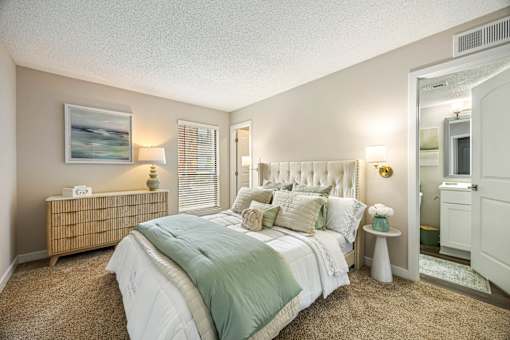 A bedroom with a bed, nightstand, and a painting on the wall.