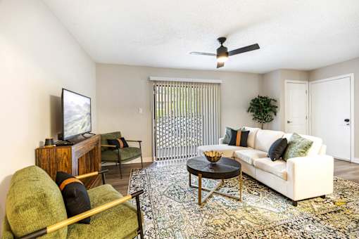 A living room with a white couch, a green chair, and a wooden cabinet.