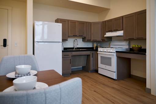 A kitchen with a white refrigerator and a dining table with two bowls on it.