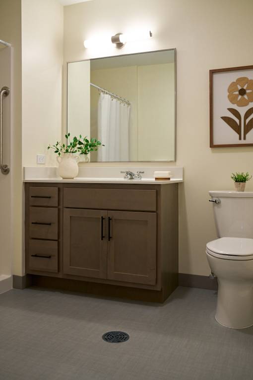 A bathroom with a toilet, sink, and mirror.