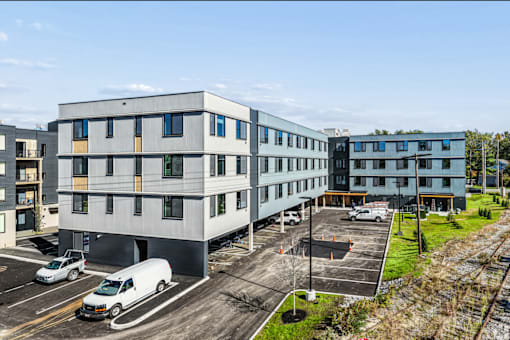 A parking lot with a white van and a grey building in the background.