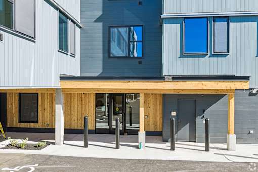 A modern building with a grey and blue exterior and a wooden entrance.