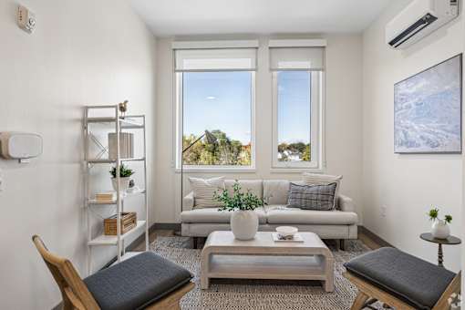 A living room with a couch, a chair, a table, and a window.