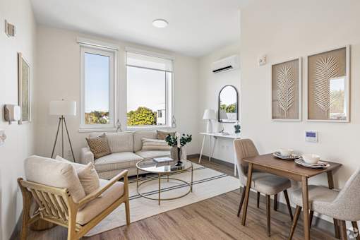 A well-lit living room with a sofa, chair, and dining table.