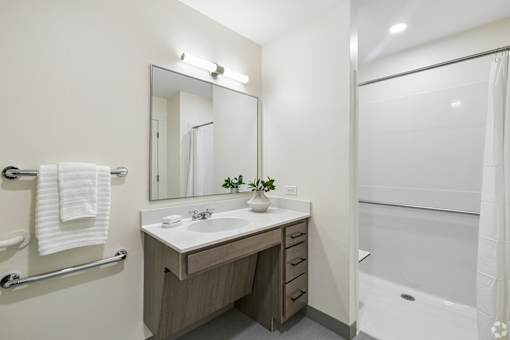 A bathroom with a sink, mirror, and bathtub.