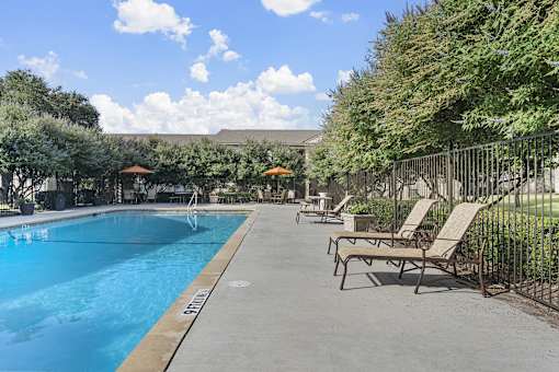 Resort style swimming pool with lounge chairs at Parks on the Green Apartments, Texas