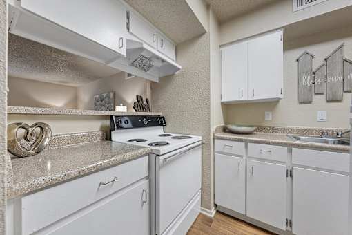 White kitchen with electric stove and overhead cabinets at Parks on the Green Apartments, Temple, TX 76504