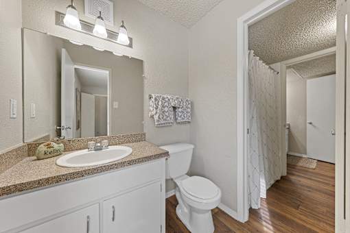 Bathroom with vanity and wood style flooring at Parks on the Green Apartments, Texas