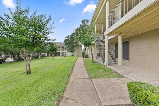 Exterior walkway between apartment buildings with landscaping at Parks on the Green Apartments, Temple, Texas