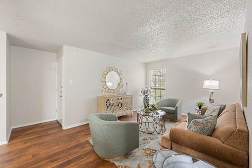 Living room with wood style flooring and decorative mirror at Parks on the Green Apartments, Texas
