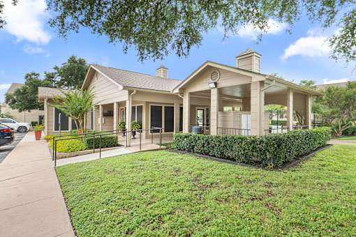 Clubhouse building with covered porch and landscaping at Parks on the Green Apartments, Texas