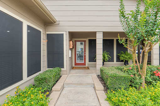 Covered front entry with potted ferns and landscaping at Parks on the Green Apartments, Temple, 76504