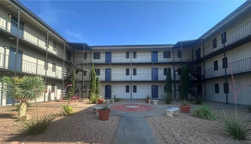 A courtyard with a red circle in the middle and plants around.
