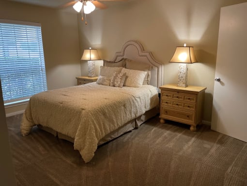 a bedroom with a bed and two nightstands and a window  at Summit Ridge Apartments, Texas, 76502