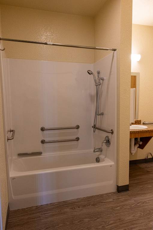 A white bathtub with a shower head and hand held shower.