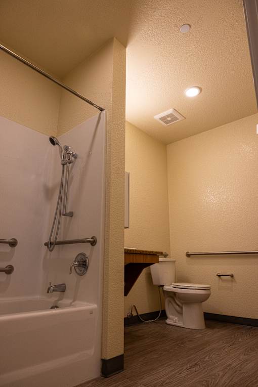 A white bathtub with a shower head and a white toilet in a bathroom.