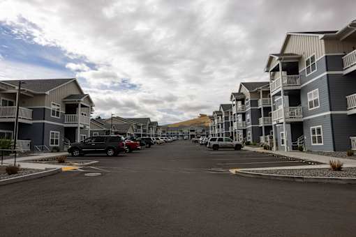 A street view of a residential area with cars parked on the side.