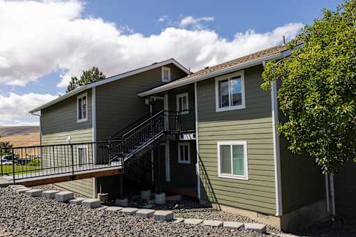 A house with a grey siding and a black metal staircase.