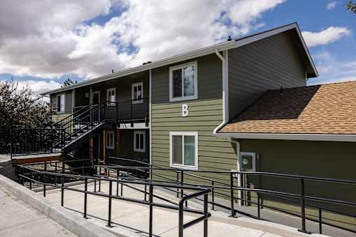 A green building with a balcony and a staircase leading to it.