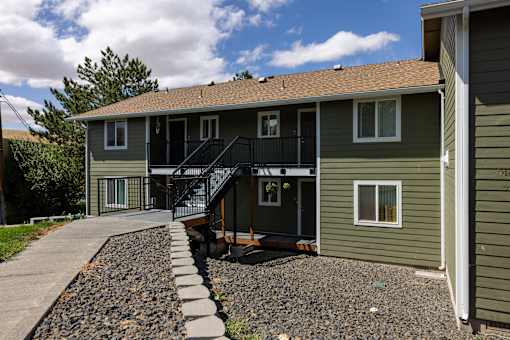 A house with a green siding and a black metal staircase.