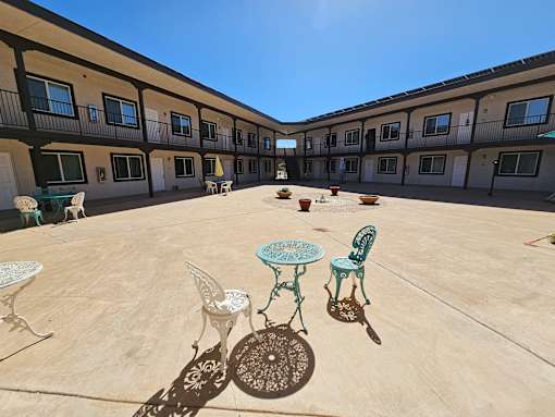 A courtyard with a table and chairs and a dog.