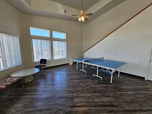 A room with a table, chairs, and a ceiling fan.