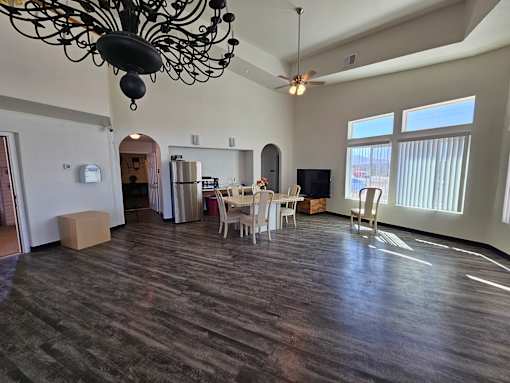 A large empty room with a chandelier and a ceiling fan.