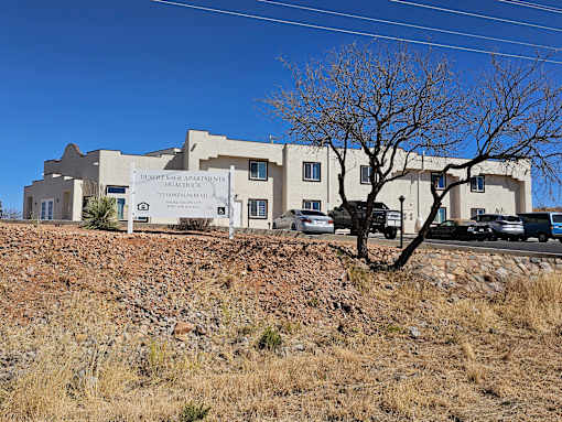 A large building with a sign that says Desert Rose Apartments on it.