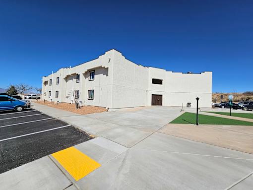 A white building with a parking lot in front.