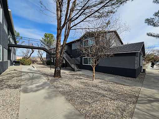 A modern house with a black exterior and a gravel driveway.