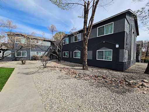 A black building with a gravel driveway in front.