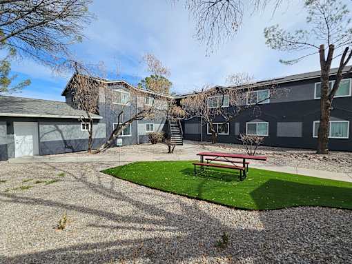 A building with a grey roof and a red bench in front of it.
