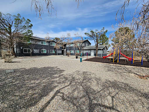 A playground with a slide and a building in the background.