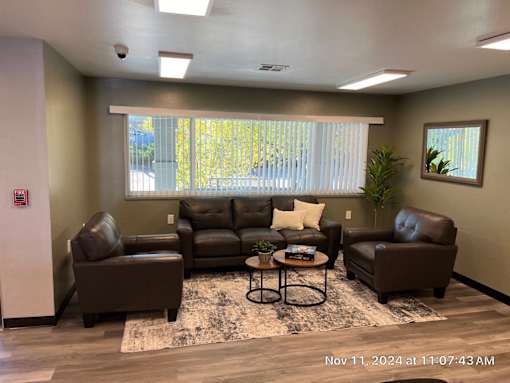 A living room with brown leather furniture and a rug.