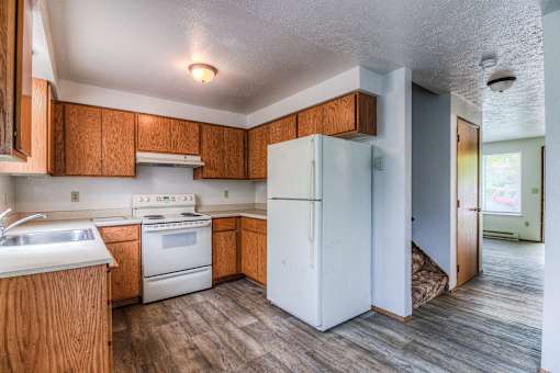 A kitchen with a white fridge and wooden cabinets.