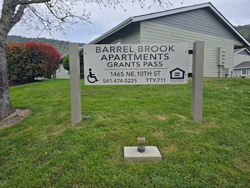 A sign for Barrel Brook Apartments stands in front of a building.