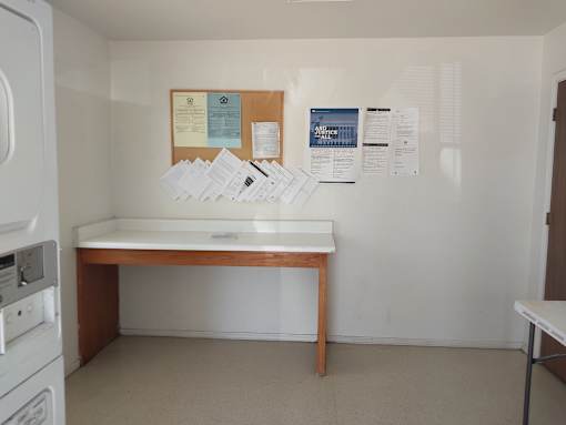 A white wall with a bulletin board and papers on it.