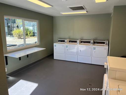 A room with a window, a bench, and a row of white cabinets.