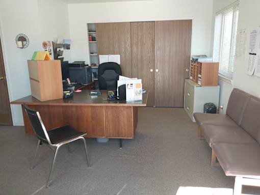 A room with a brown desk, a brown couch, and a brown chair.