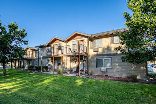 A large house with a balcony and a green lawn in front.