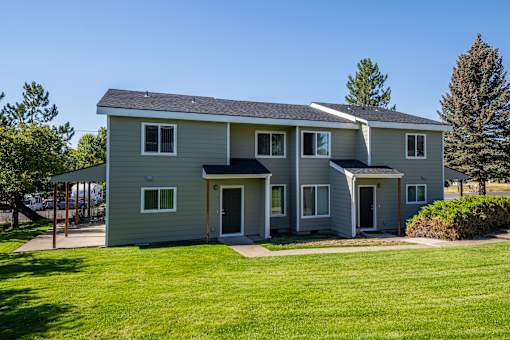 A grey house with a green lawn in front.