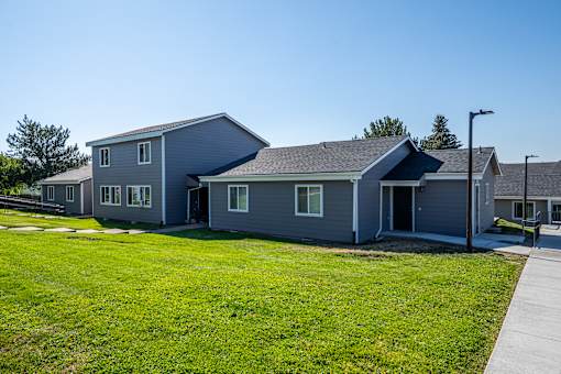 A grey house with a green lawn in front.