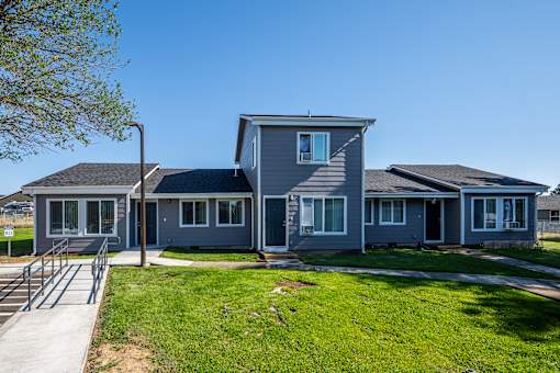 A grey house with a green lawn in front.