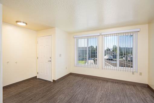 A room with a white door and a window with a view of a parking lot.