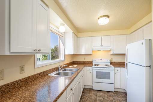 A kitchen with white cabinets and a brown counter top.