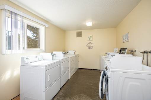 A laundry room with a washer and dryer on the left and a washer and dryer on the right.