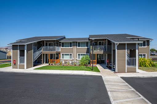 A modern two-story apartment building with a parking lot in front.