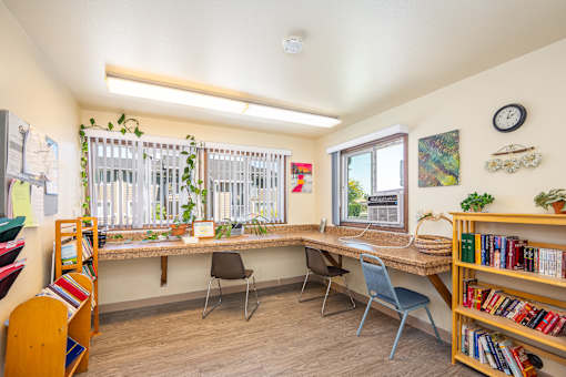 A room with a desk, chairs, and a bookshelf.